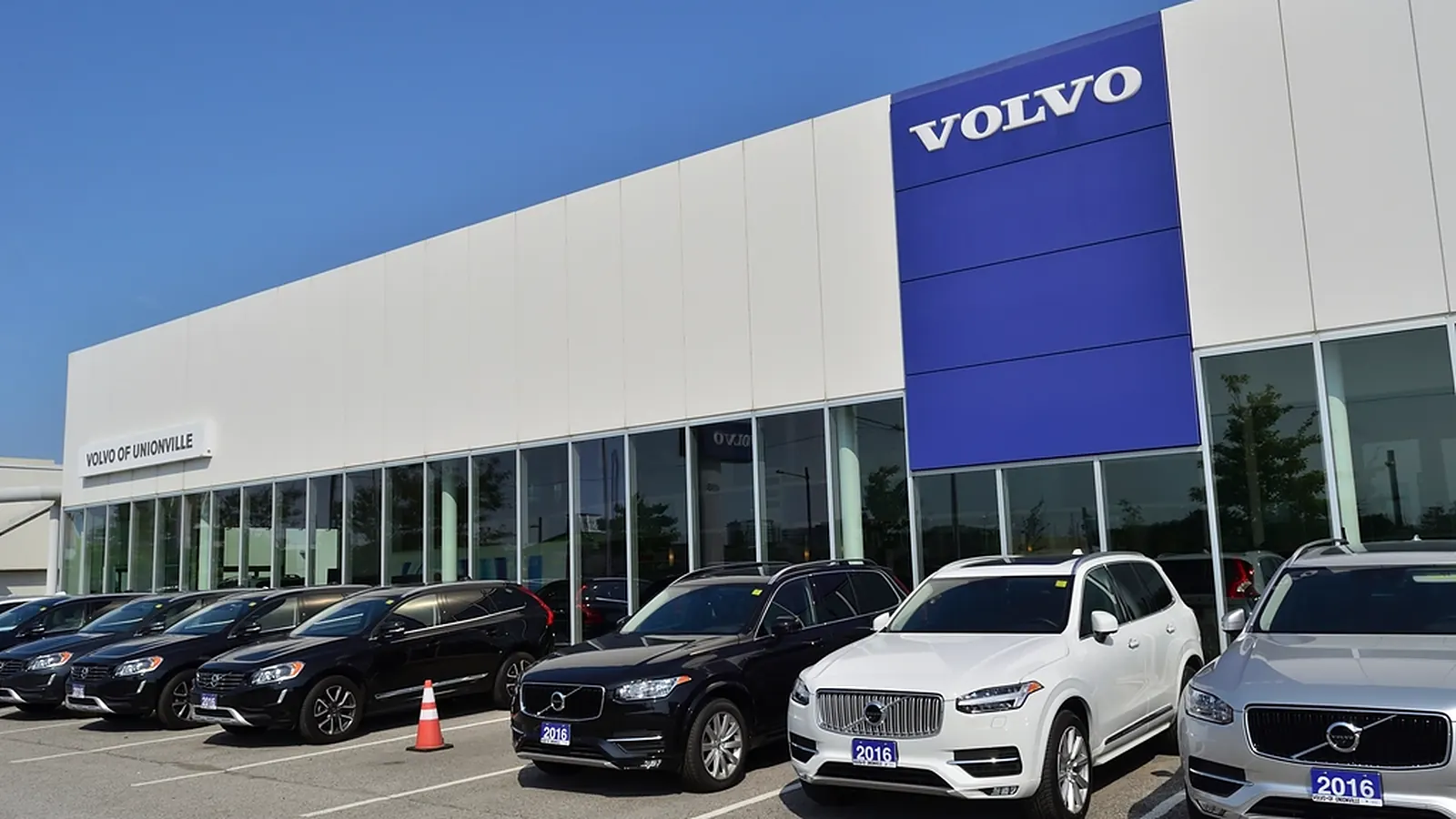 Automobilių salonas su naujais automobiliais aikštelėje prie pastato
