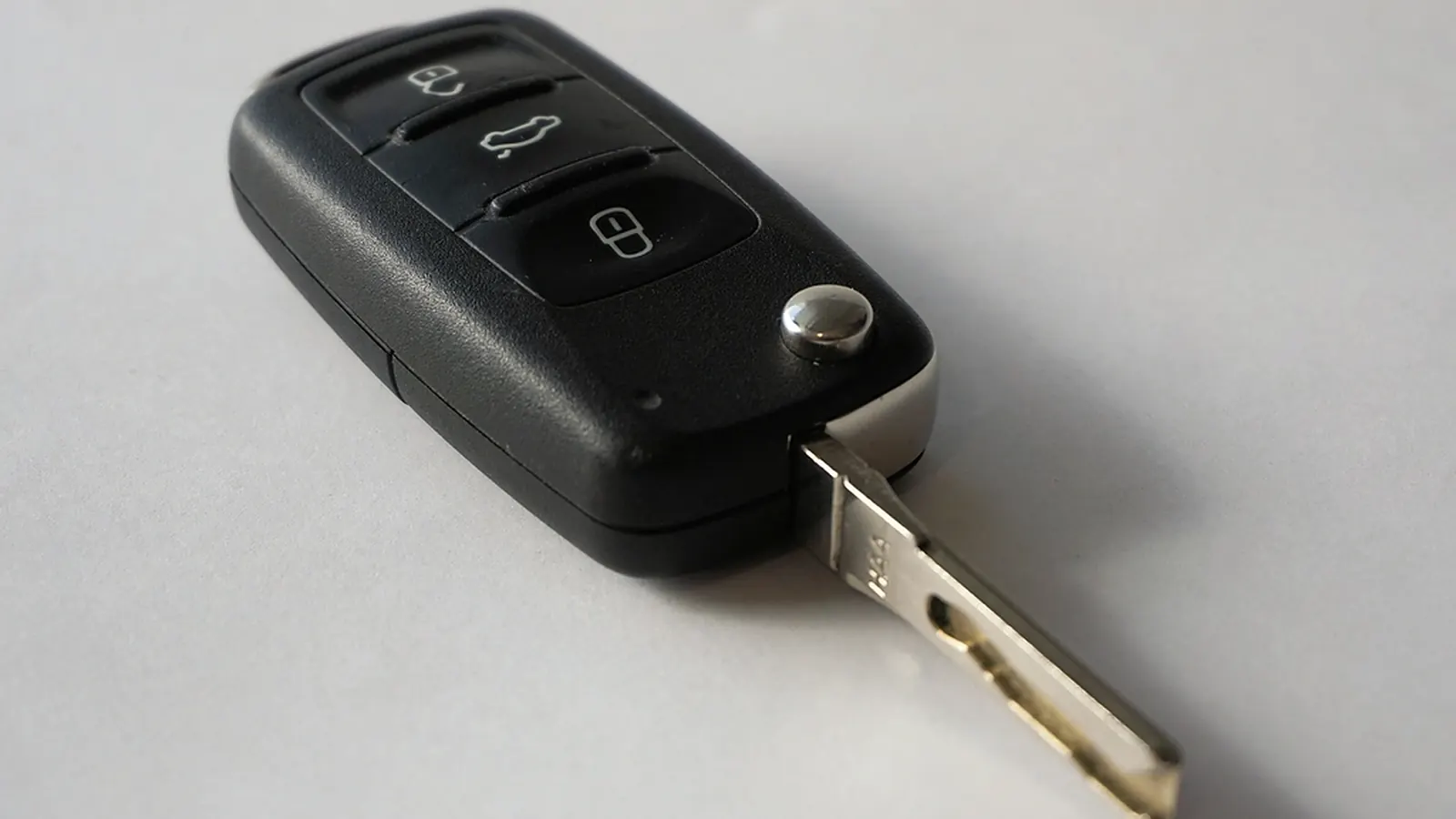 Juodas sulankstomas automobilio raktelis gulintis ant šviesaus stalo